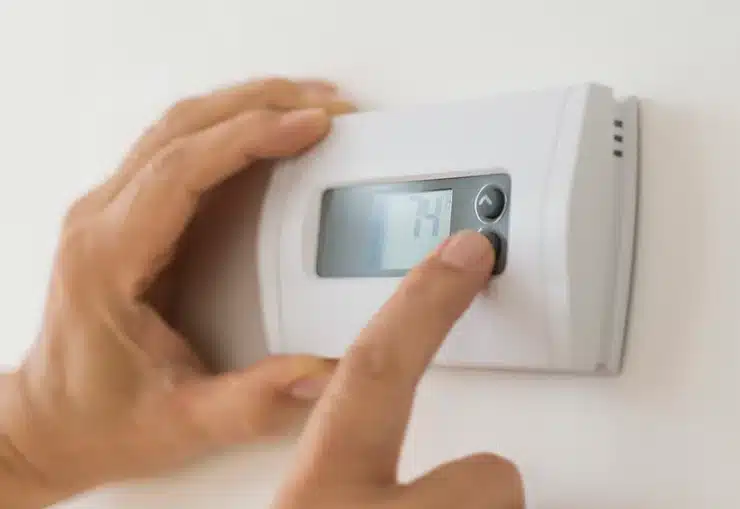 hands turning thermostat down